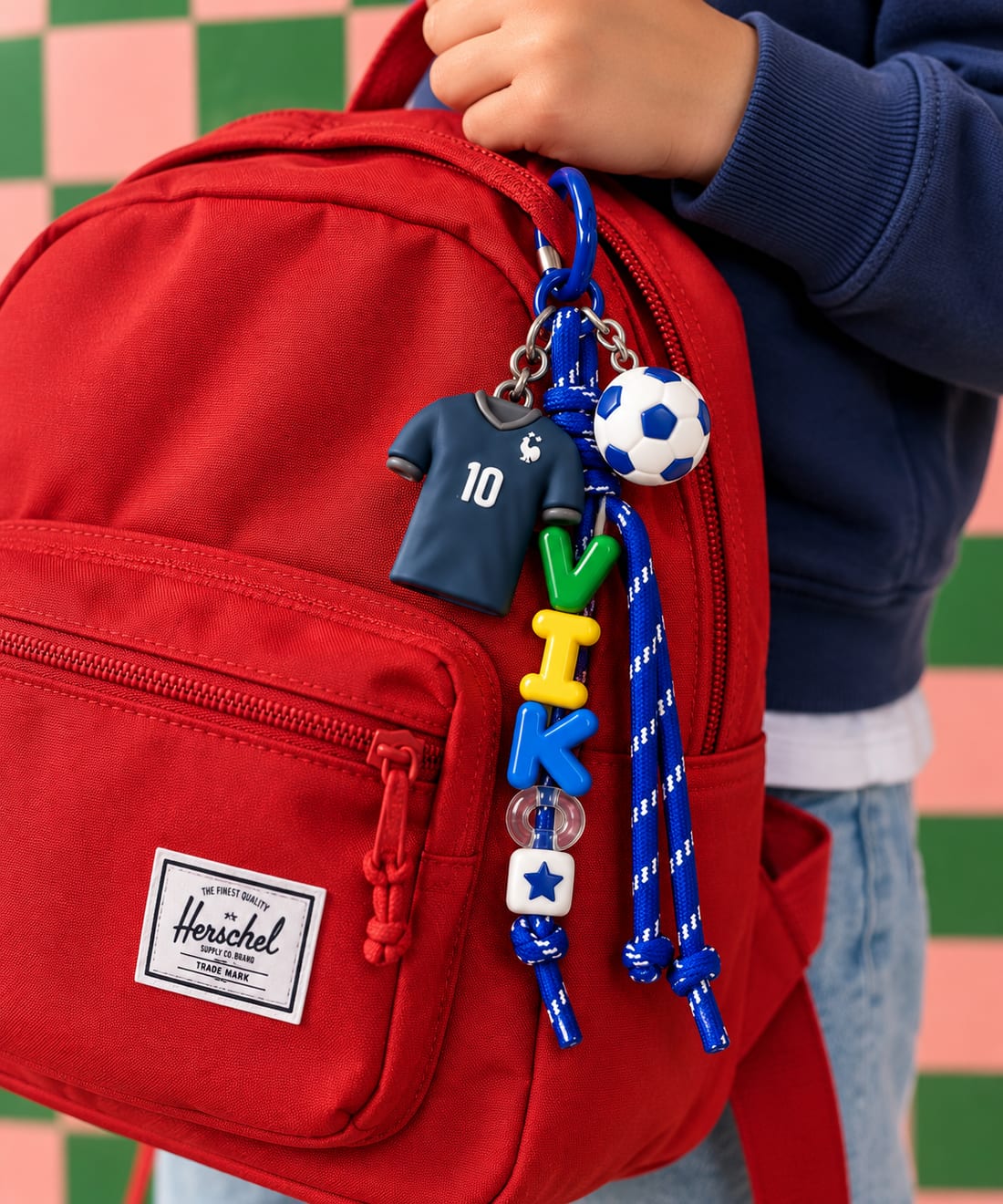 Rode rugzak met een blauwe bag charm met de naam VIK, voetbalshirt en bal